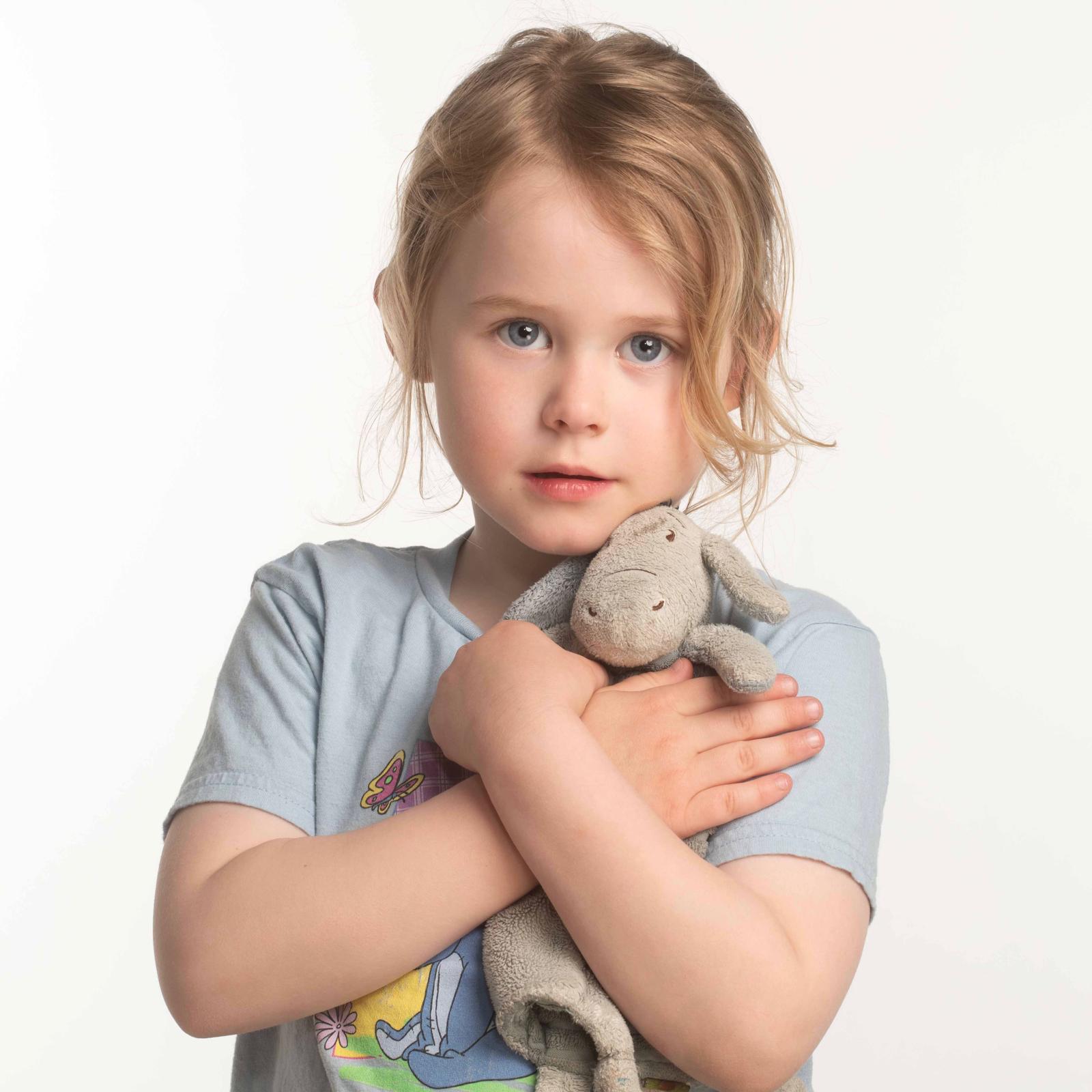 Young girl holding a plush toy against a white background