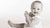 Black and white photo of a baby sitting on a white background