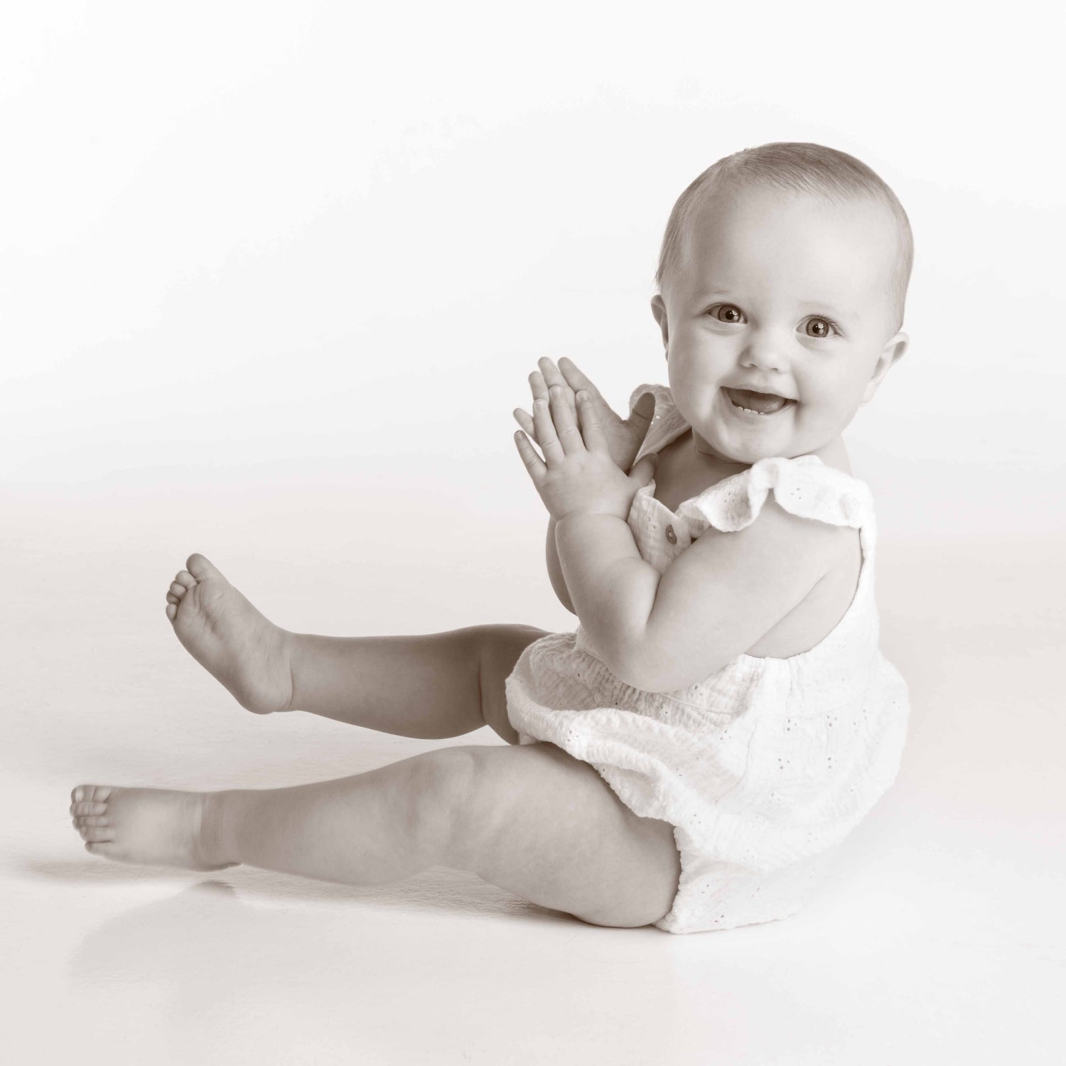 Black and white photo of a baby sitting on a white background