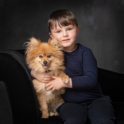 Portrait in colour of a little boy and his small golden Pomeranian dog