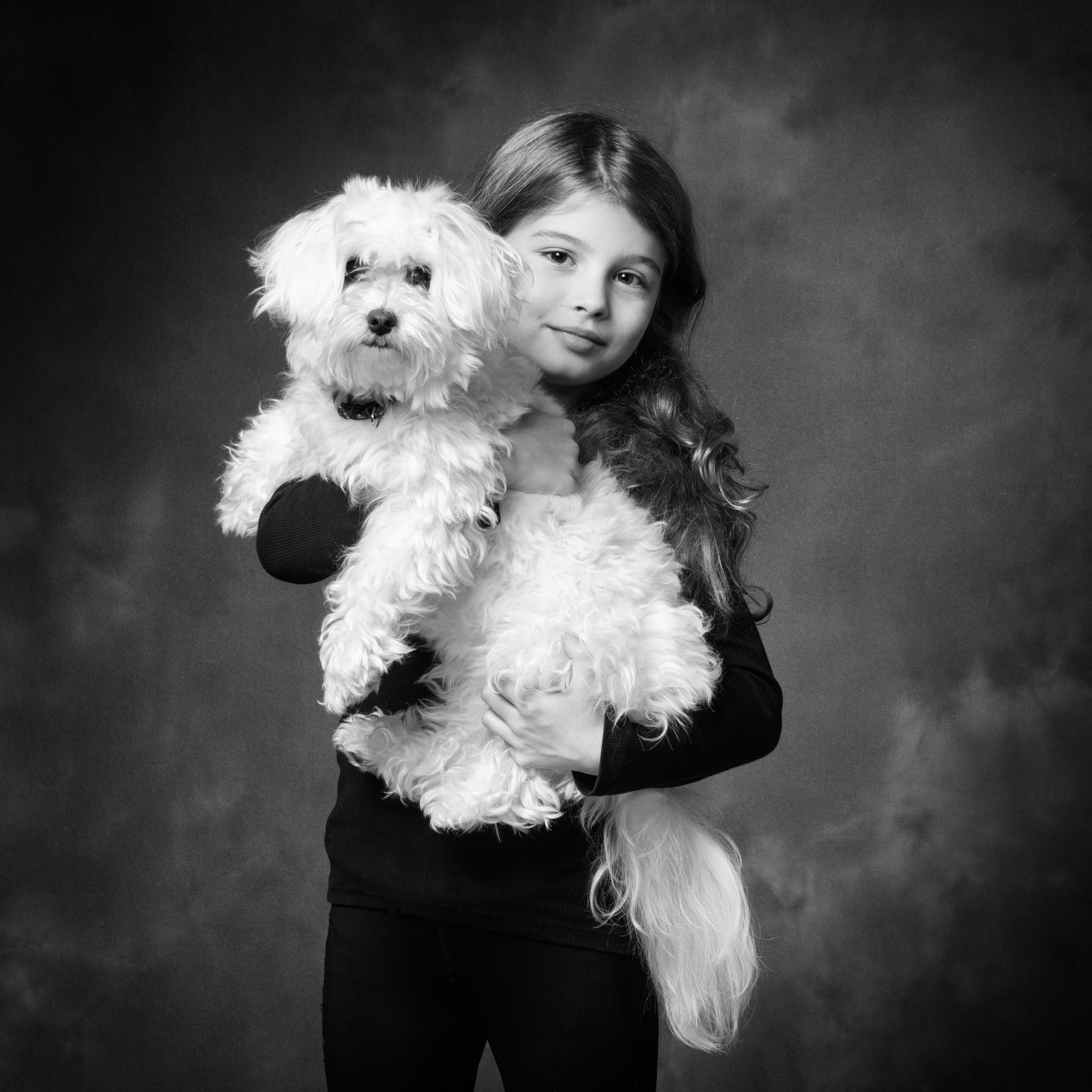 Portrait in black and white of a little girl and her small white dog