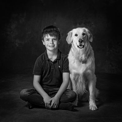 Portrait in black and white of a boy and his golden Retriever dog sitting side by side  PHOTOGENIC Dalkey